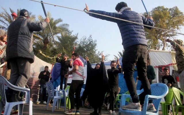 Iraqi anti-government protesters flash the V-sign of victory outside their protest tents in Baghdad's Tahrir Square following news of the killing of Iranian Revolutionary Guards top commander Qasem Soleimani in a US strike on his convoy at Baghdad international airport on January 3, 2020 (AFP)